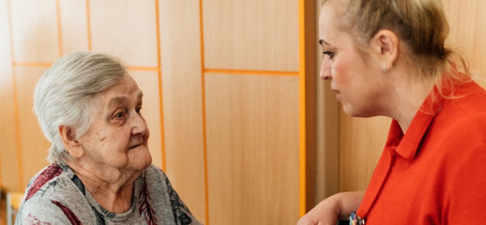 Carer gently assisting an elderly woman with her walking frame, symbolising attentive personal care